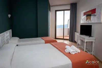a bedroom with two beds and a tv and a window at Hotel Bruc in El Bruc