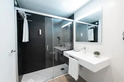 a bathroom with two sinks and a glass shower at Aparthotel Atenea Barcelona in Barcelona