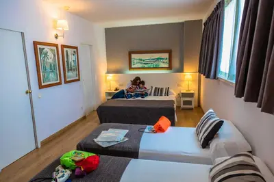 a woman sitting on a bed reading a book at Aparthotel Atenea Barcelona in Barcelona