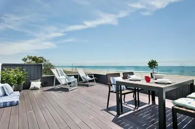 a wooden deck with a table and chairs on a balcony at Apartamentos Marfina in Castelldefels