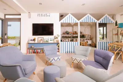 a living room with blue and white chairs and a tv at Apartamentos Marfina in Castelldefels