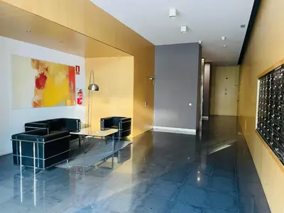 a lobby with chairs and a table in a building at Fira de Barcelona City View Apartment with Garage Parking in Hospitalet de Llobregat