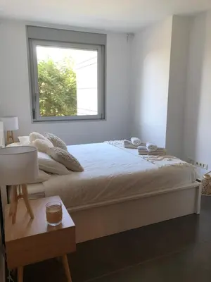 a white bedroom with a large bed with a window at Standing Apartment Barcelona Forum in Sant Adria de Besos