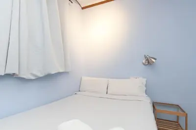 a small white room with a bed and a window at Homenfun Barcelona Eixample I in Barcelona