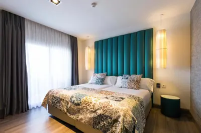 a bedroom with a large bed with a green headboard at Sant Jordi Boutique Hotel in Calella
