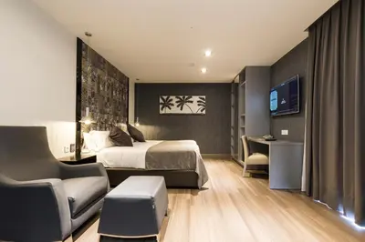 a hotel room with a bed and a chair and a tv at Sant Jordi Boutique Hotel in Calella