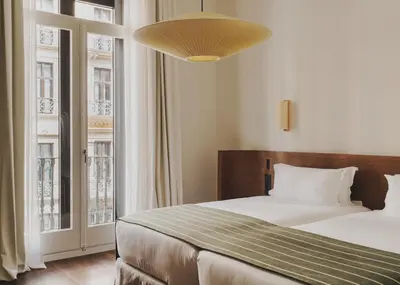a bedroom with a bed and a large window at Hotel Regina Barcelona in Barcelona