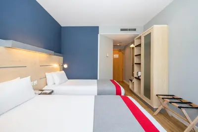 a bedroom with two beds and a blue wall at Holiday Inn Express Barcelona - Montmeló by IHG in Granollers