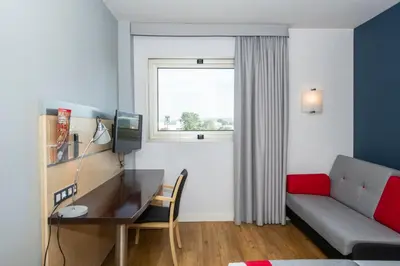 a room with a couch and a desk and a window at Holiday Inn Express Barcelona - Montmeló by IHG in Granollers