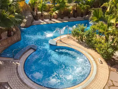a swimming pool with blue water and palm trees at Hotel Blancafort Spa Termal in La Garriga