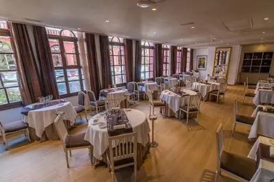 a dining room with tables and chairs and windows at Hotel Blancafort Spa Termal in La Garriga