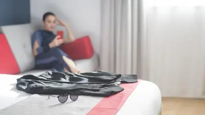a person sitting on a bed with a pair of glasses at Holiday Inn Express Molins de Rei by IHG in Molins de Rei