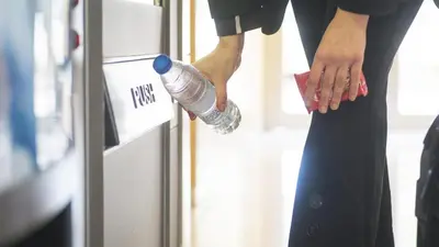 a person holding a bottle of water on a refrigerator at Holiday Inn Express Molins de Rei by IHG in Molins de Rei