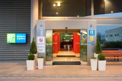 a building with red doors and potted plants in front at Holiday Inn Express Molins de Rei by IHG in Molins de Rei