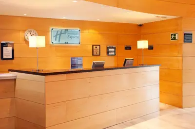 a lobby with a counter with a clock on the wall at Holiday Inn Express Molins de Rei by IHG in Molins de Rei