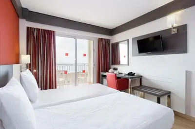 a hotel room with a white bed and a desk at Medplaya Hotel Santa Monica in Calella