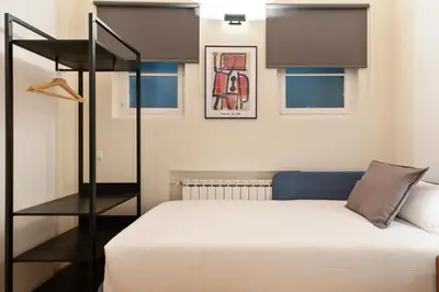 a small bedroom with a bed and a black shelf at Señor Urgell Apartment by Olala Homes in Barcelona