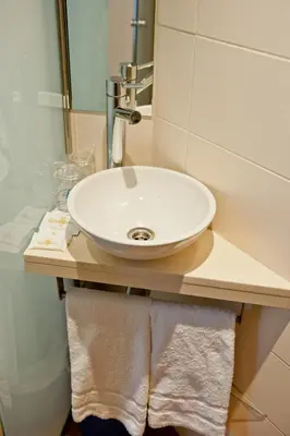 a white sink in a bathroom with towels on a counter at Hostal Marenostrum in Barcelona