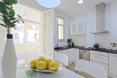 a white kitchen with a plate of lemons on a table at CENTRAL & BRIGHT APARTMENT!! in Barcelona