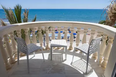 a balcony with chairs and a table and the ocean at URH Sitges Playa in Sitges