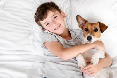 a young girl laying in bed with a dog at URH Sitges Playa in Sitges