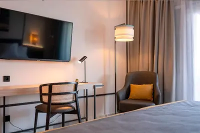 a hotel room with a desk and a chair and a tv at URH Sitges Playa in Sitges