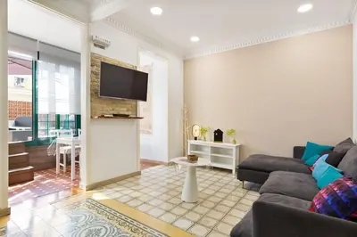 a living room with a couch and a tv on a wall at Bright Apt with Private Terrace in Sant Antoni in Barcelona