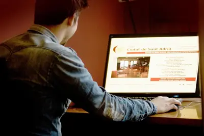 a man sitting at a table using a laptop computer at Hotel Ciutat De Sant Adria in Sant Adria de Besos