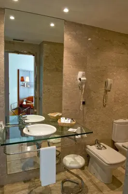 a bathroom with two sinks and a toilet and a phone at Best Western Hotel Mediterraneo in Castelldefels