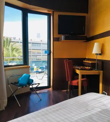 a hotel room with a bed and a desk and a television at Best Western Hotel Mediterraneo in Castelldefels