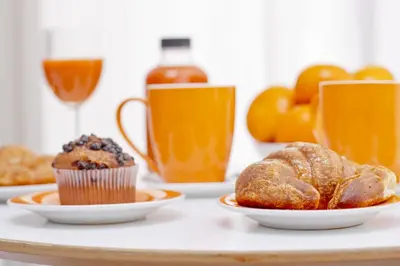 a table with plates of pastries and cups of orange juice at Barcelona City Centre Hostal in Barcelona