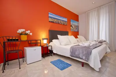 a bedroom with orange walls and a bed and a chair at Barcelona City Centre Hostal in Barcelona