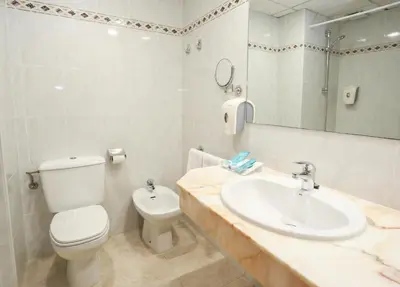 a bathroom with a white toilet and a sink at KAKTUS Hotel Volga in Calella