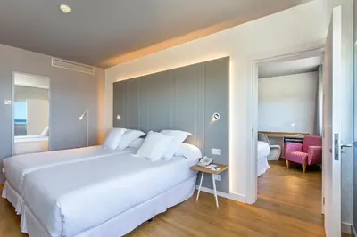 a bedroom with a large white bed and a table at Occidental Atenea Mar - Adults Only in Barcelona