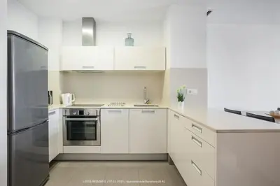 a kitchen with white cabinets and a stainless steel refrigerator at Flateli Navas D01 in Barcelona