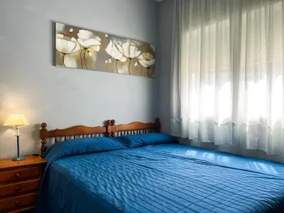 a bedroom with a bed with a blue blanket and a window at Vivalidays Casa Ricardo in Sant Cebrià de Vallalta