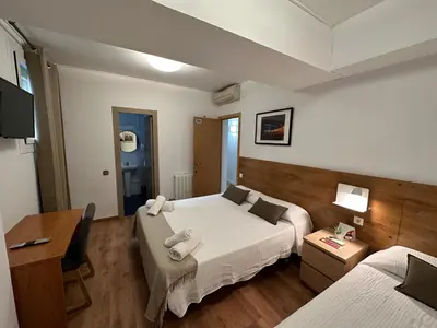 a hotel room with two beds and a desk at Hostal Alogar in Barcelona