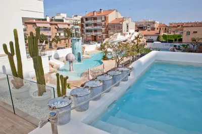 a swimming pool with cactus and plants on a building at FERGUS Club Pineda Splash in Pineda de Mar