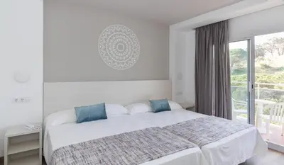 a white bedroom with a bed and a window at Hotel Oasis Park Splash in Calella
