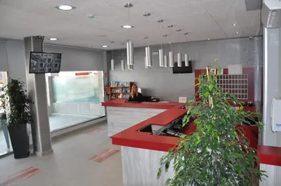 a restaurant lobby with a red counter and plants at Aparthotel Safari in Calella