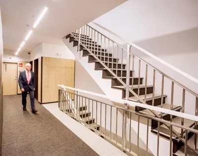 a man in a suit walking down a hallway with stairs at Aparthotel Silver in Barcelona