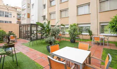a patio with tables and chairs and a building at Aparthotel Silver in Barcelona