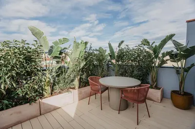 a table and chairs on a balcony with plants at Petit Luxe Volta ÀTIC in Terrassa