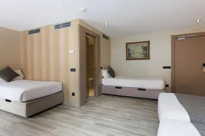 a hotel room with two beds and a closet at Hotel Suizo in Barcelona