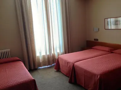 a hotel room with two beds and a window at Hotel Pelayo in Barcelona