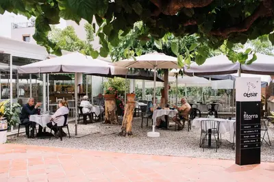 a group of people sitting at tables under umbrellas at Cèsar in Vilanova i la Geltrú