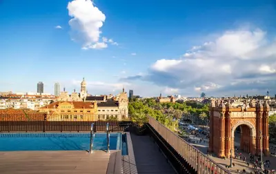 a pool on the roof of a building with lounge chairs at Archie Living in Barcelona