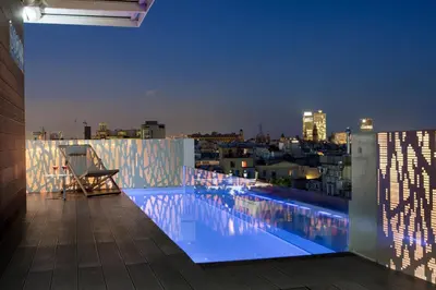 a swimming pool on the roof of a building at night at Gaudi Hotel in Barcelona
