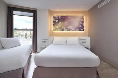 two beds in a room with a painting on the wall at Eurostars Don Cándido in Terrassa
