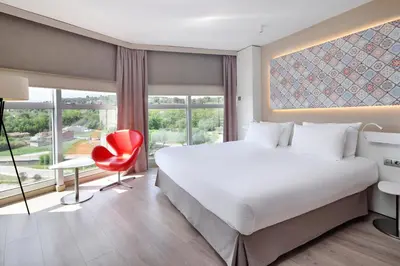 a bedroom with a large bed and a red chair at Eurostars Don Cándido in Terrassa